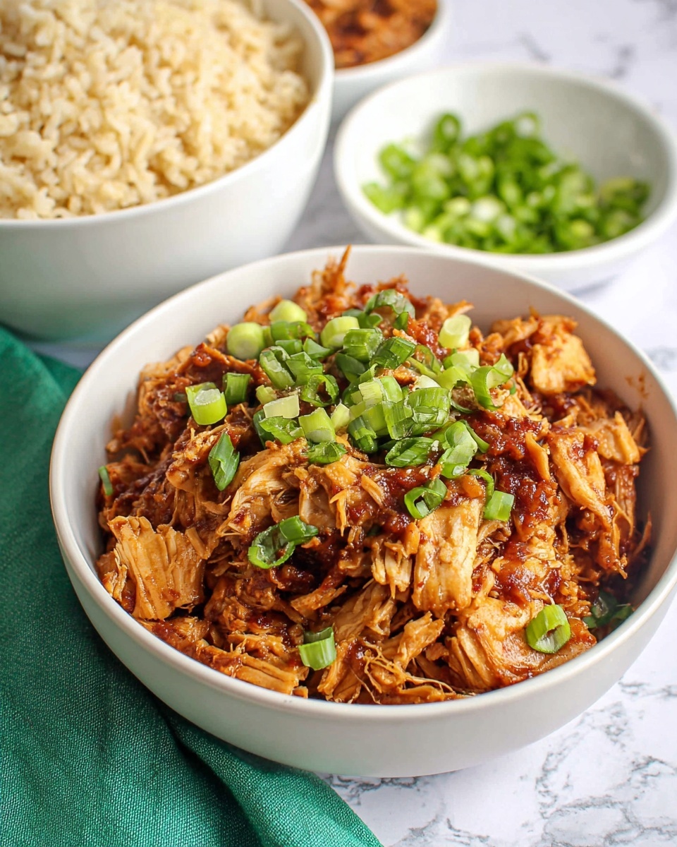 A white bowl filled with shredded, cooked chicken pieces in a glossy, dark brown sauce, topped with a small pile of bright green chopped spring onions in the center; above and to the left, there is a white bowl filled with light brown cooked rice, and above and to the right, a small white bowl contains more chopped bright green spring onions; the background shows a white marbled surface with a white cloth and a bit of a green cloth visible near the bottom right corner; a small green dish with peanuts is partially visible at the bottom left corner; photo taken with an iphone --ar 4:5 --v 7
