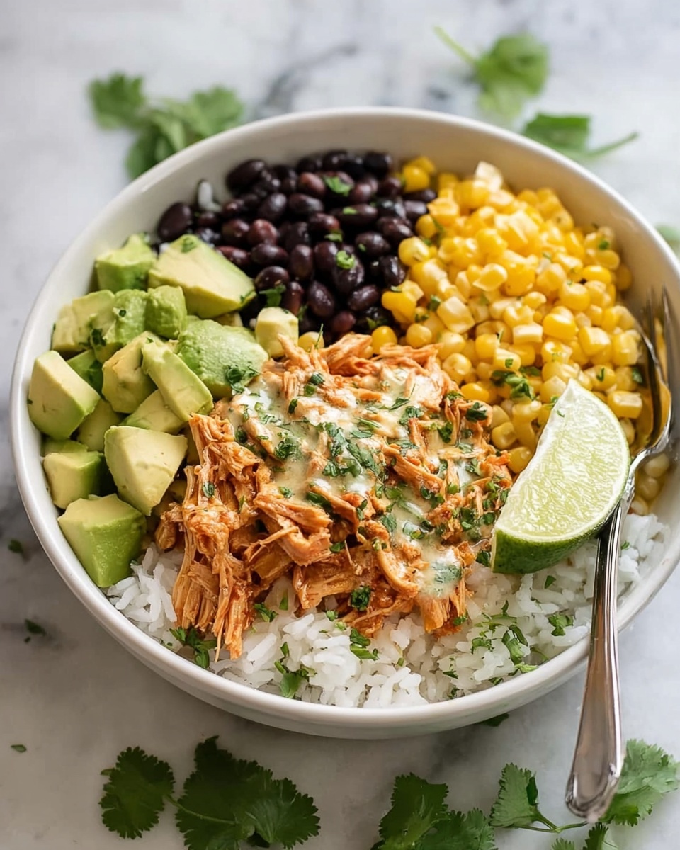Slow Cooker Chicken Burrito Bowl Recipe 5 A white bowl filled with a base layer of white rice, topped with four sections: shredded orange-brown chicken mixed with light green sauce and sprinkled with fresh green herbs at the center, bright yellow corn kernels on the right, dark black beans on the left, and green avocado chunks at the top left. A fresh green lime wedge sits on the right edge of the bowl. A silver fork rests inside the bowl near the corn. The bowl is placed on a white marbled surface with scattered green cilantro leaves and a white cloth with gray stripes in the background. A small glass bowl with green sauce is partially visible behind the main bowl. Photo taken with an iphone --ar 4:5 --v 7