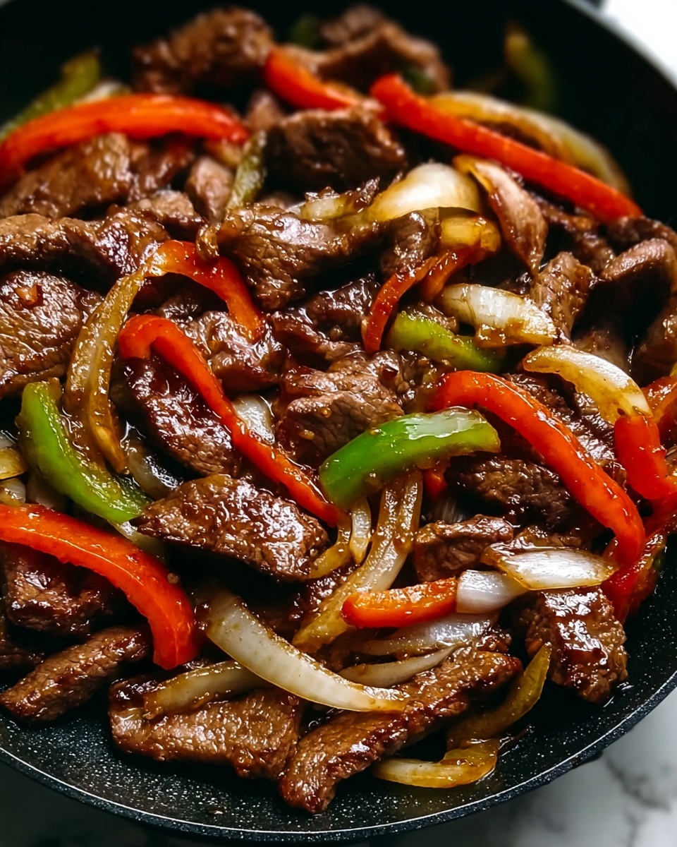 This image shows a close-up of cooked beef strips mixed with sliced onions and bell peppers in a black pan. The beef pieces are brown and shiny, showing a juicy texture. The sliced onions are translucent white and slightly browned at the edges, while the bell peppers add a pop of color with red and green strips spread evenly throughout the dish. The pan’s edge is visible, emphasizing the hot and fresh nature of the food. The background is a white marbled texture. photo taken with an iphone --ar 4:5 --v 7