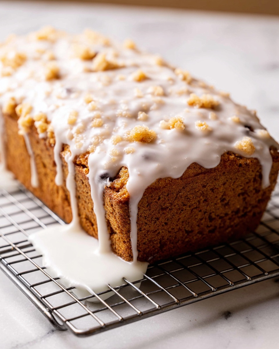 Moist Lemon Blueberry Loaf with Lemon Glaze Recipe 5 A loaf of golden brown bread with a rough crumbly texture on top, covered in a thick, white icing that drips down the sides onto a white plate beneath it. The icing is smooth and glossy, with small crumbles scattered across its surface. The loaf sits on a metal cooling rack over a white marbled surface, with the icing pooling slightly on the plate below photo taken with an iphone --ar 4:5 --v 7