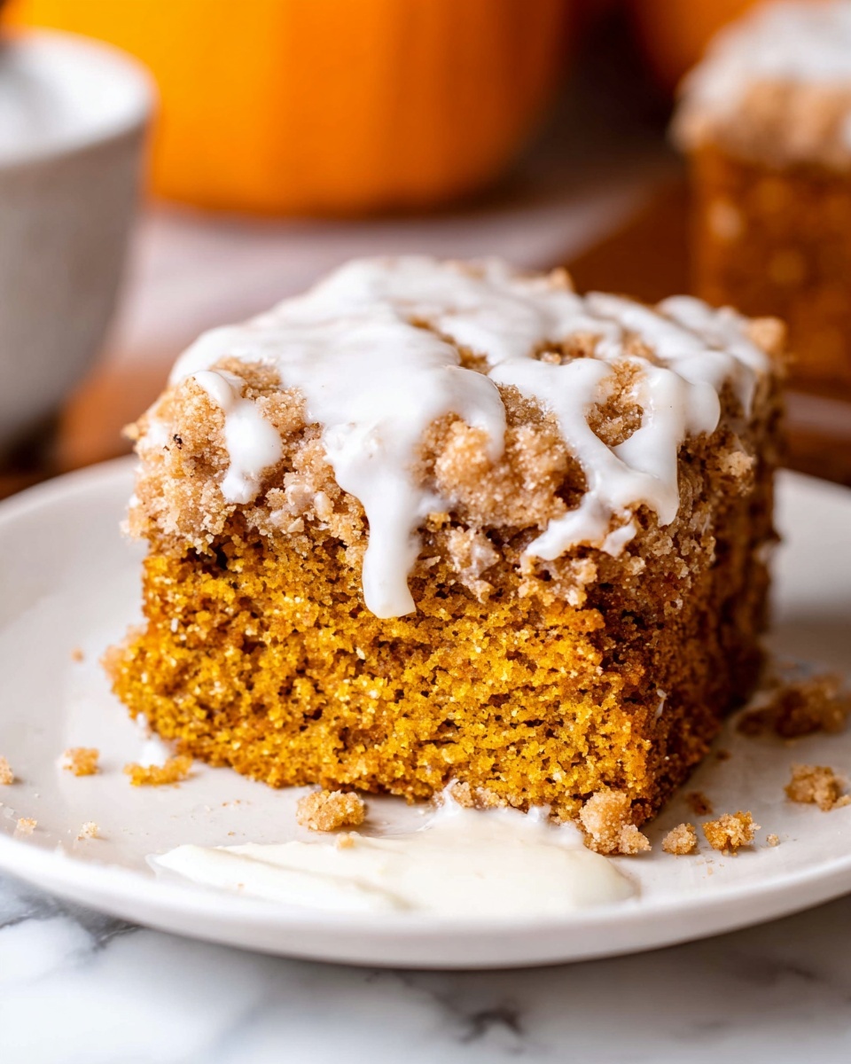 A close-up view of a baked dessert in a white square dish with thick edges and handles. The dish shows one main layer that is a crumbly, golden brown topping with a rough, chunky texture. It is scattered unevenly, showing lighter patches of a white glaze drizzled across the top. The background shows blurred small orange pumpkins and a few cinnamon sticks placed nearby on a white marbled surface. The scene is bright and cozy, with warm tones highlighting the dessert's crispy topping. photo taken with an iphone --ar 4:5 --v 7