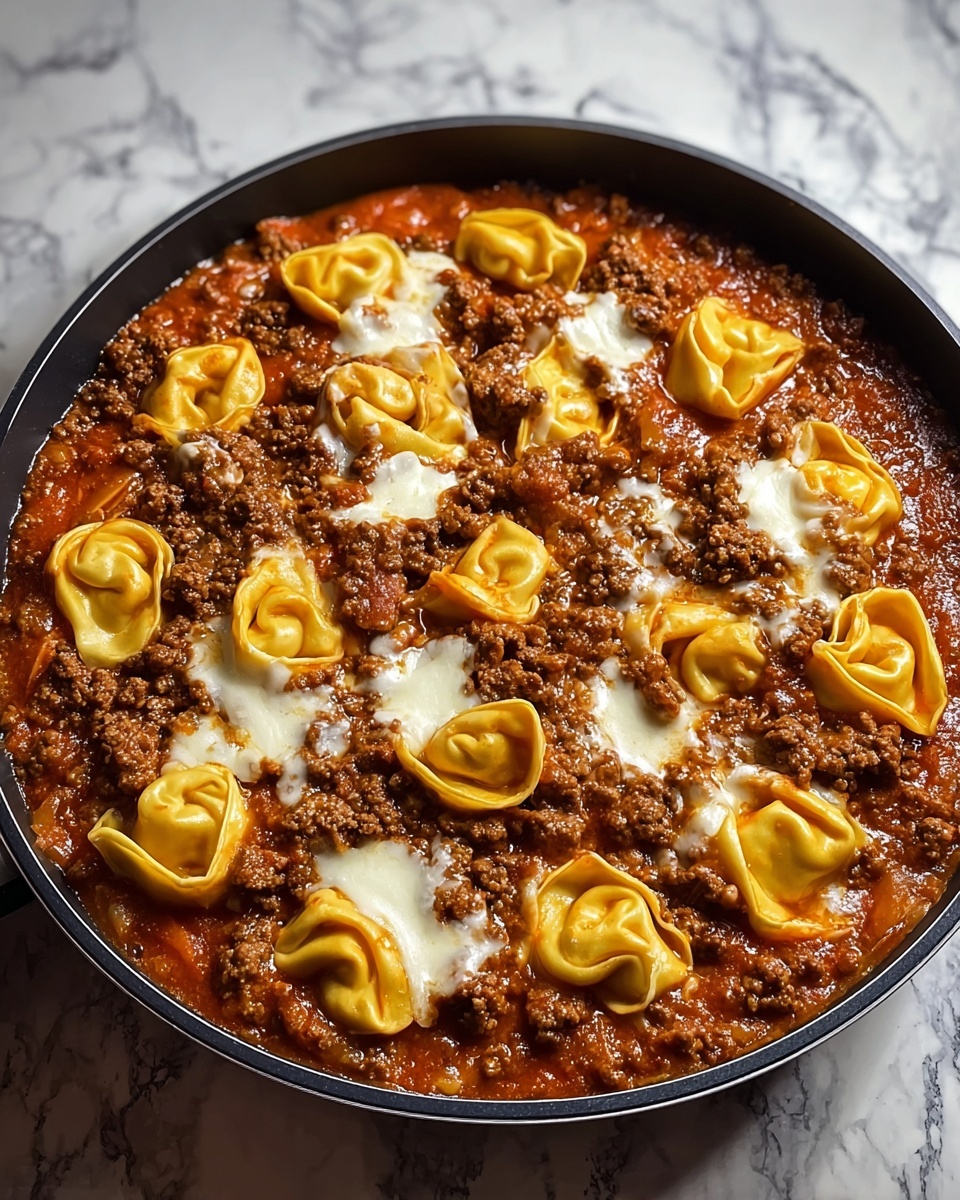 A round black pan filled with a thick, rich tomato sauce mixed with browned ground meat spreads evenly across the bottom. Over this layer, there are multiple tortellini pasta pieces, golden yellow in color with a smooth, slightly glossy texture, partially submerged in the sauce. Scattered on top of the meat and pasta are uneven patches of melted white cheese that look soft and creamy, blending slightly into the sauce but still distinct. The pan is placed on a white marbled countertop, with a subtle shadow around it. photo taken with an iphone --ar 4:5 --v 7