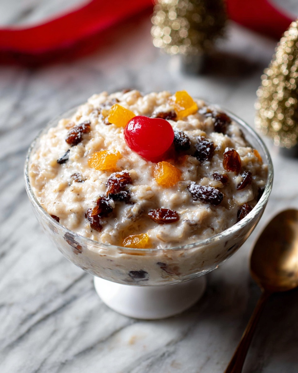 Single white bowl showcasing a close-up, intimate serving of creamy rice pudding studded with plump raisins and small, vibrant golden-orange candied fruit pieces, the smooth and slightly textured pudding visible with a dusting of cinnamon on top, natural light highlighting the soft glossy finish, placed on a white marble surface with a blurred festive background, styled as a ready-to-eat portion from a food blog, photo taken with an iphone --ar 4:5 --v 7