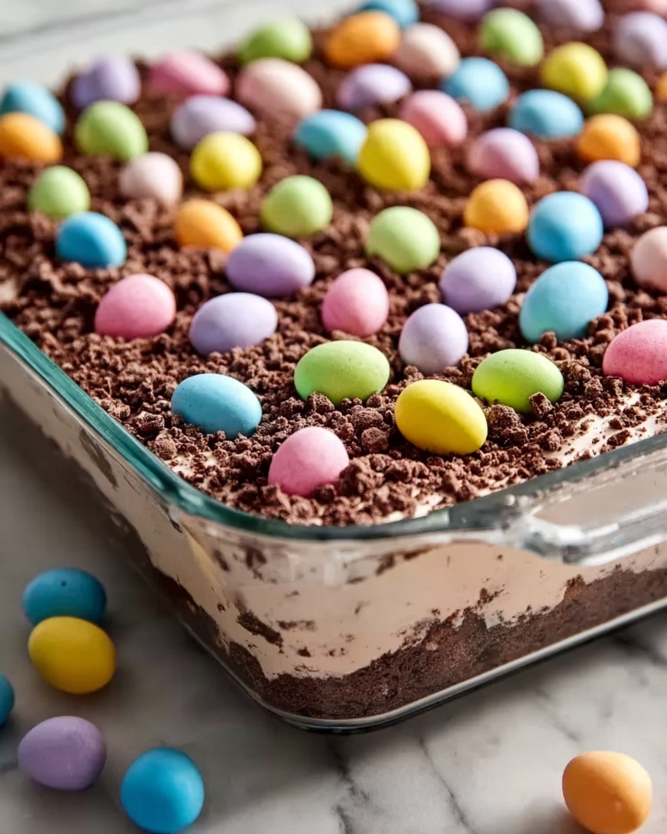 Easter Dirt Cake Casserole Recipe 6 Large white rectangular glass baking dish filled with a layered chocolate dessert featuring moist chocolate cake base, creamy chocolate frosting, and a topping of chocolate crumbles sprinkled generously with colorful pastel candy-coated chocolate eggs, arranged evenly across the surface, photographed at a 3/4 angle on a white marble countertop with natural lighting, professional food styling photo taken with an iphone --ar 4:5 --v 7