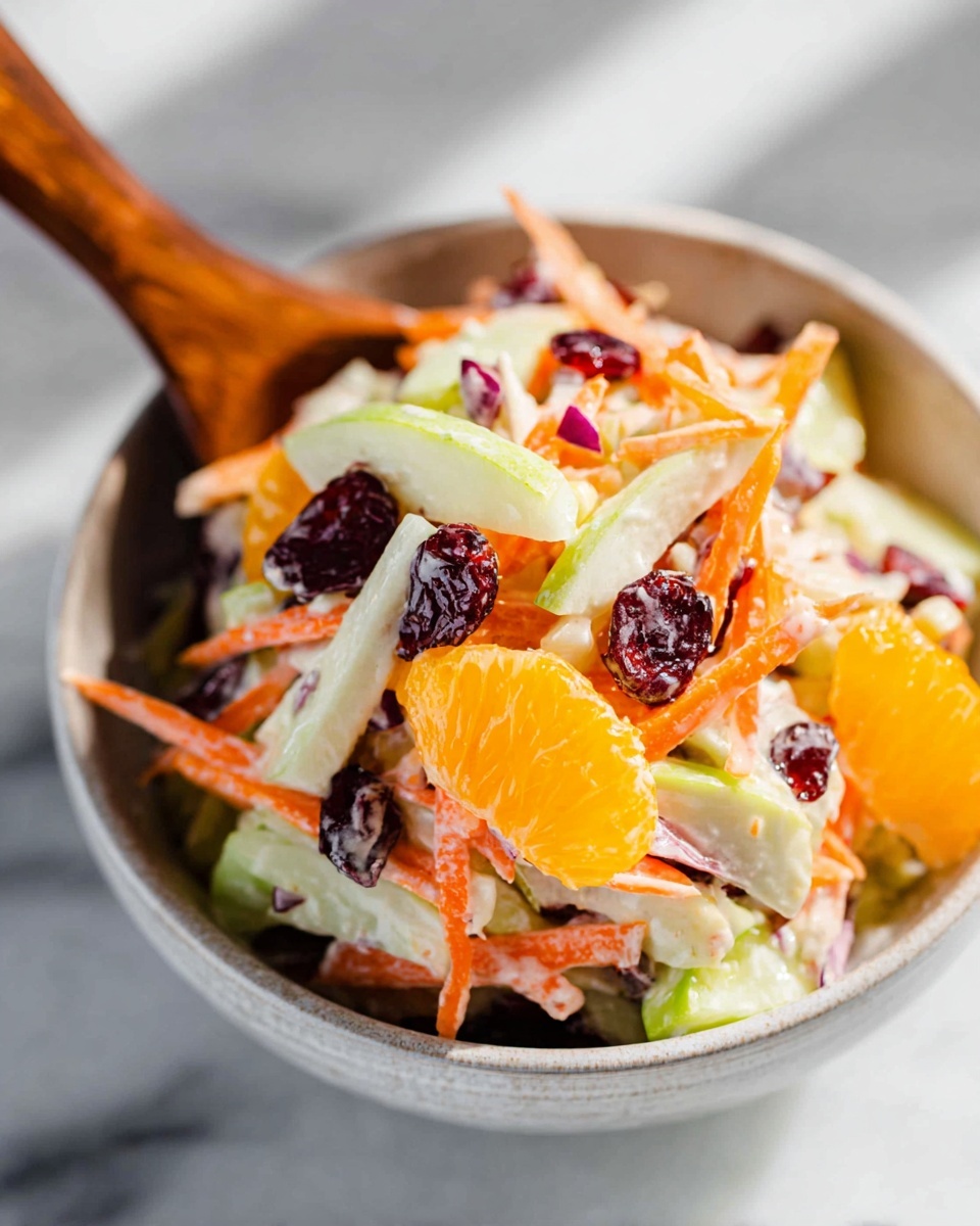 Large white bowl filled with a vibrant and colorful Waldorf salad combining crisp apple slices, bright orange mandarin segments, shredded carrots, celery pieces, dried cranberries, and chopped nuts, all expertly tossed in a creamy dressing, presented on a white marble countertop with natural lighting, photographed at a professional 3/4 angle to capture the full dish in frame, styled as a hero shot from a food magazine, photo taken with an iphone --ar 4:5 --v 7