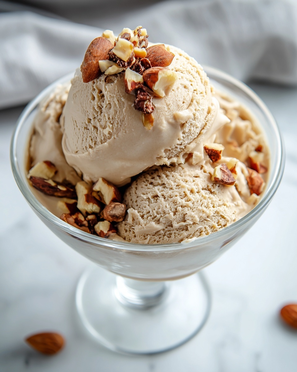 A large white serving bowl filled generously with rich, creamy homemade coffee ice cream, perfectly scooped into several rounded mounds and sprinkled evenly with chopped toasted almonds, presented as a complete dish on a pristine white marble surface, captured in natural light from a professional 3/4 angle, styled like a hero shot in a food magazine, photo taken with an iphone --ar 4:5 --v 7